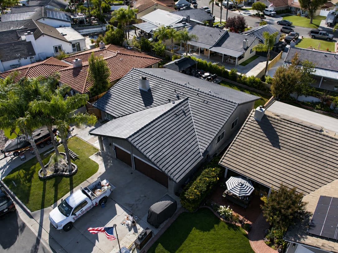 Aerial drone view of a completed concrete-tile roof replacement by TMC Roofing in Southern California, TMC truck in the driveway
